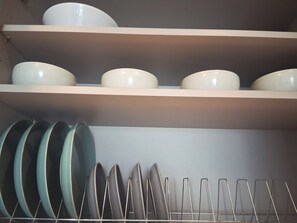 Een koelkast, een kookplaat, kookgerei, borden en bestek