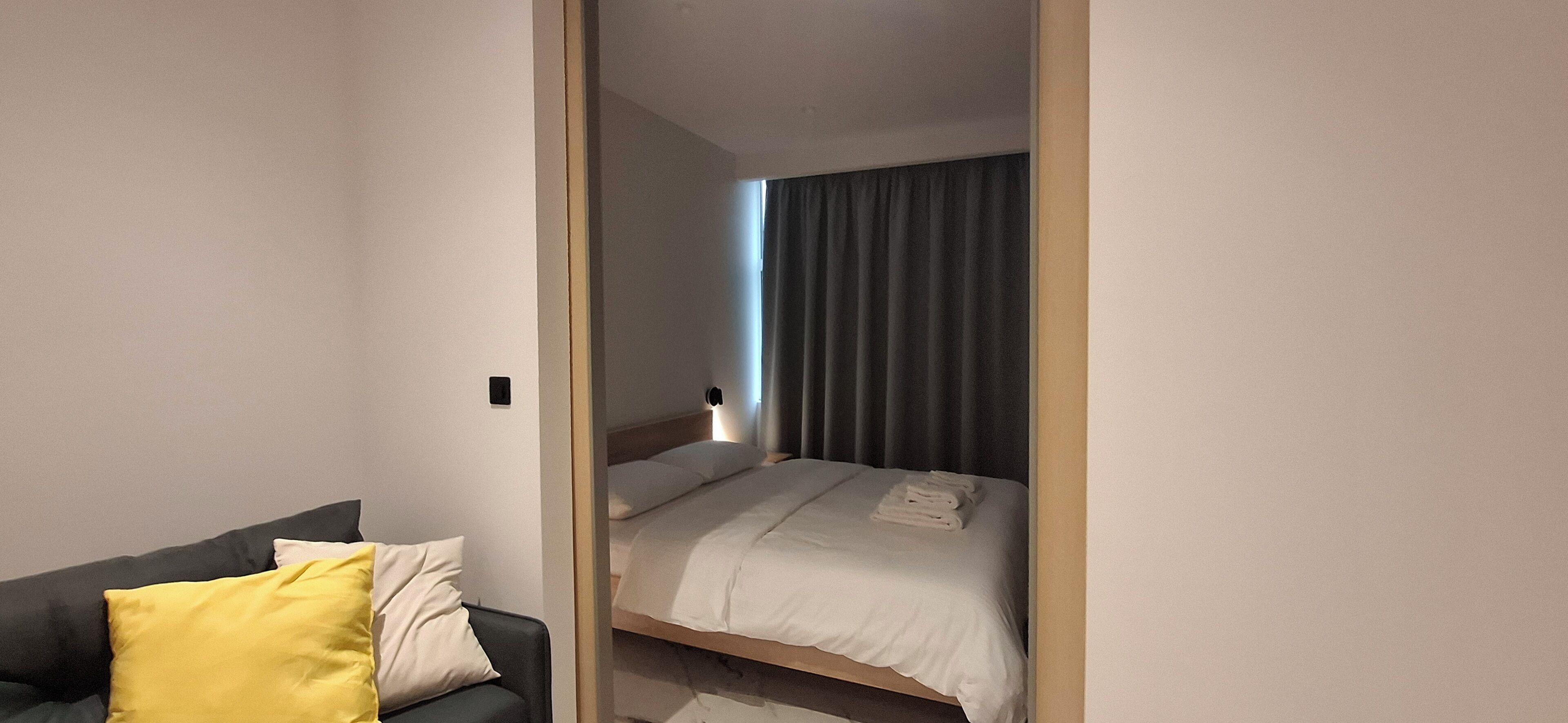 A hotel room with a bed, a bedside table, a chair, and a window with curtains.