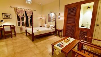 A four-poster bed with a wooden frame, a bedside table with a magazine, a chair, and a dining table with a placemat.