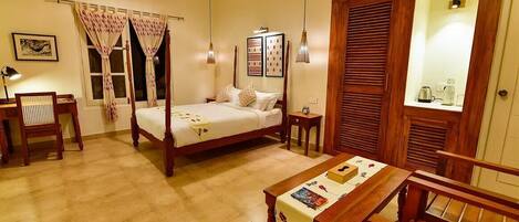 A four-poster bed with a wooden frame, a bedside table with a magazine, a chair, and a dining table with a placemat.