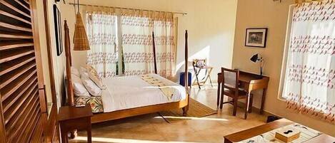 A bedroom with a bed, a desk, and a chair, a ceiling fan, and a hanging light fixture.