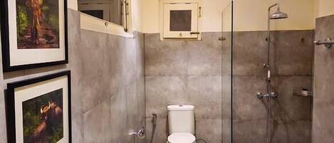 A modern bathroom with a toilet, shower, and framed pictures on the wall.