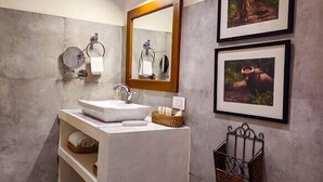 A modern bathroom with a large sink, a mirror, and two framed pictures on the wall. - Musafir Jungle Resort (Sarupeta)