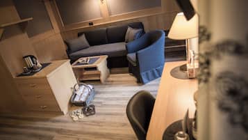 A compact, well-lit room with a wooden floor, a sofa, a small table, and a chair.
