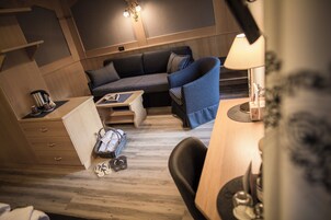 Una habitación compacta y bien iluminada con suelo de madera, un sofá, una mesita y una silla.