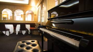 A grand piano in a warmly lit room with a bench in the foreground.