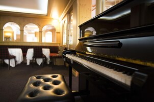 Un piano de cola en una habitación cálidamente iluminada, con un banco al frente.