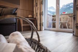Una sala de estar acogedora con un sofá, una mesa y vistas a las montañas a través de un ventanal.