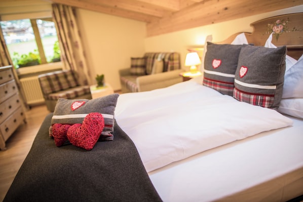 A neatly made bed with a white comforter and two pillows with heart designs. - Olympic Spa Hotel (San Giovanni di Fassa)