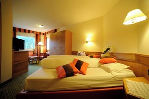 Una habitación de hotel con una cama, un escritorio, una silla, un televisor y una ventana.