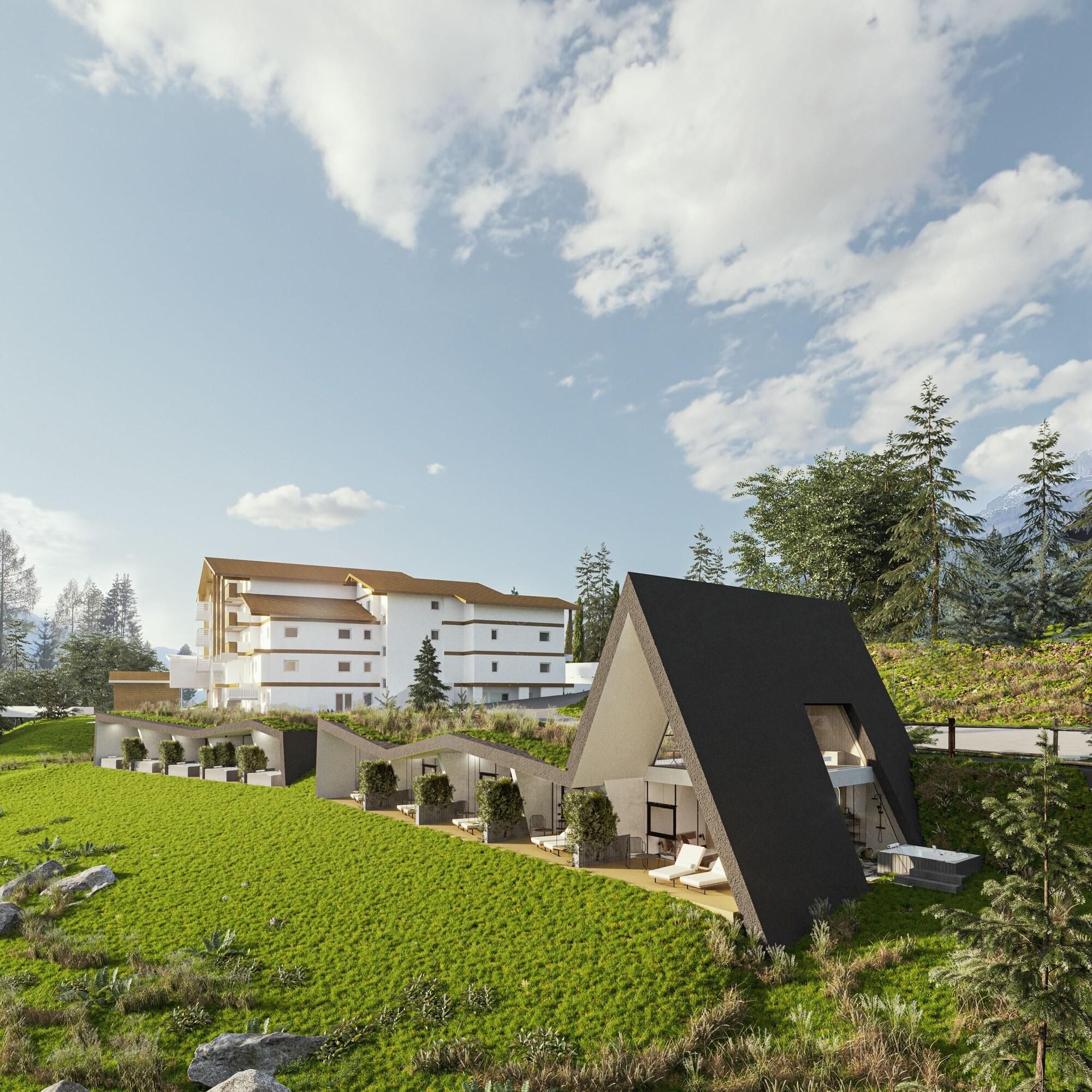 A modern building with a flat roof and a sloped roof section, surrounded by green fields and trees.