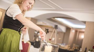 Eine Person in traditioneller Kleidung bereitet eine Kerze in einem Raum mit einem Chandelier und einem Tisch mit einer Flasche und einer Rose.