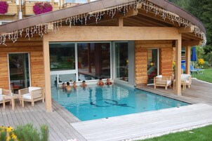 Una casa de piscina de madera con un porche cubierto y una piscina.