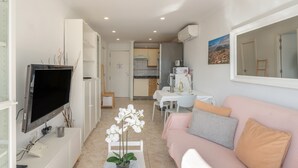 A compact living space with a TV, a sofa, a dining table, and a kitchen area. - Vacation Apartment 'Sunshine Sea' with Sea View, Wi-Fi, and Air Conditioning (Arona)