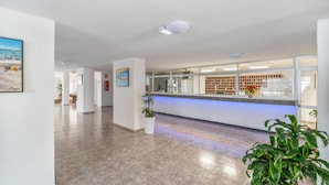 A reception area with a counter, potted plants, and a tiled floor. - Vacation Apartment 'Sunshine Sea' with Sea View, Wi-Fi, and Air Conditioning (Arona)