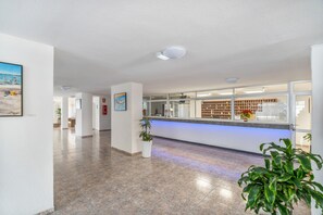 Ein Empfangsbereich mit Theke, Blumentöpfen und Fliesenboden.
