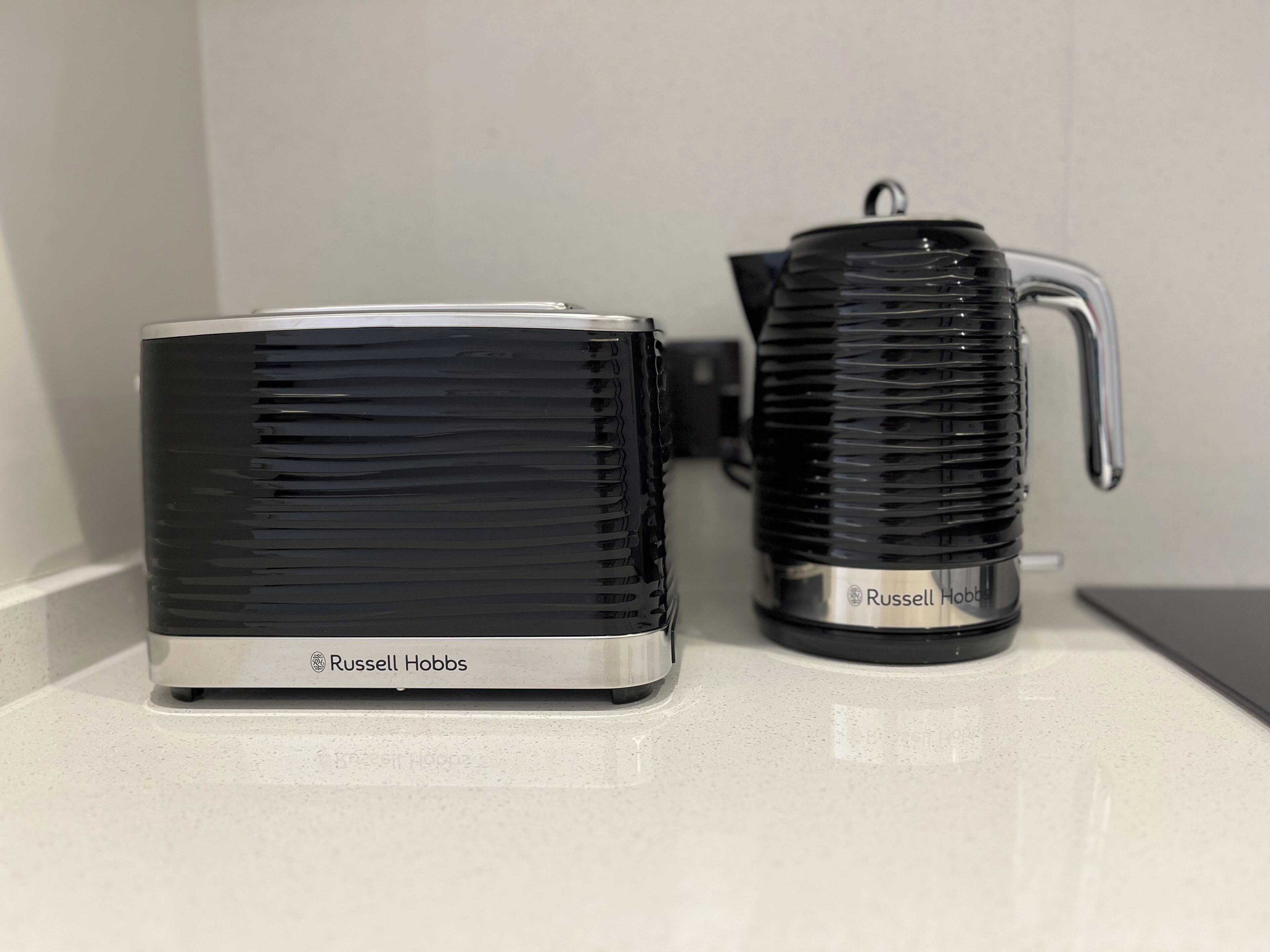 Two black and silver coffee makers, one with a handle and one without, on a countertop.