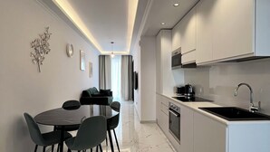 Una cocina moderna con gabinetes blancos, encimera negra y un lavamanos.