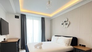 Un dormitorio moderno con una cama grande, un escritorio y un televisor.