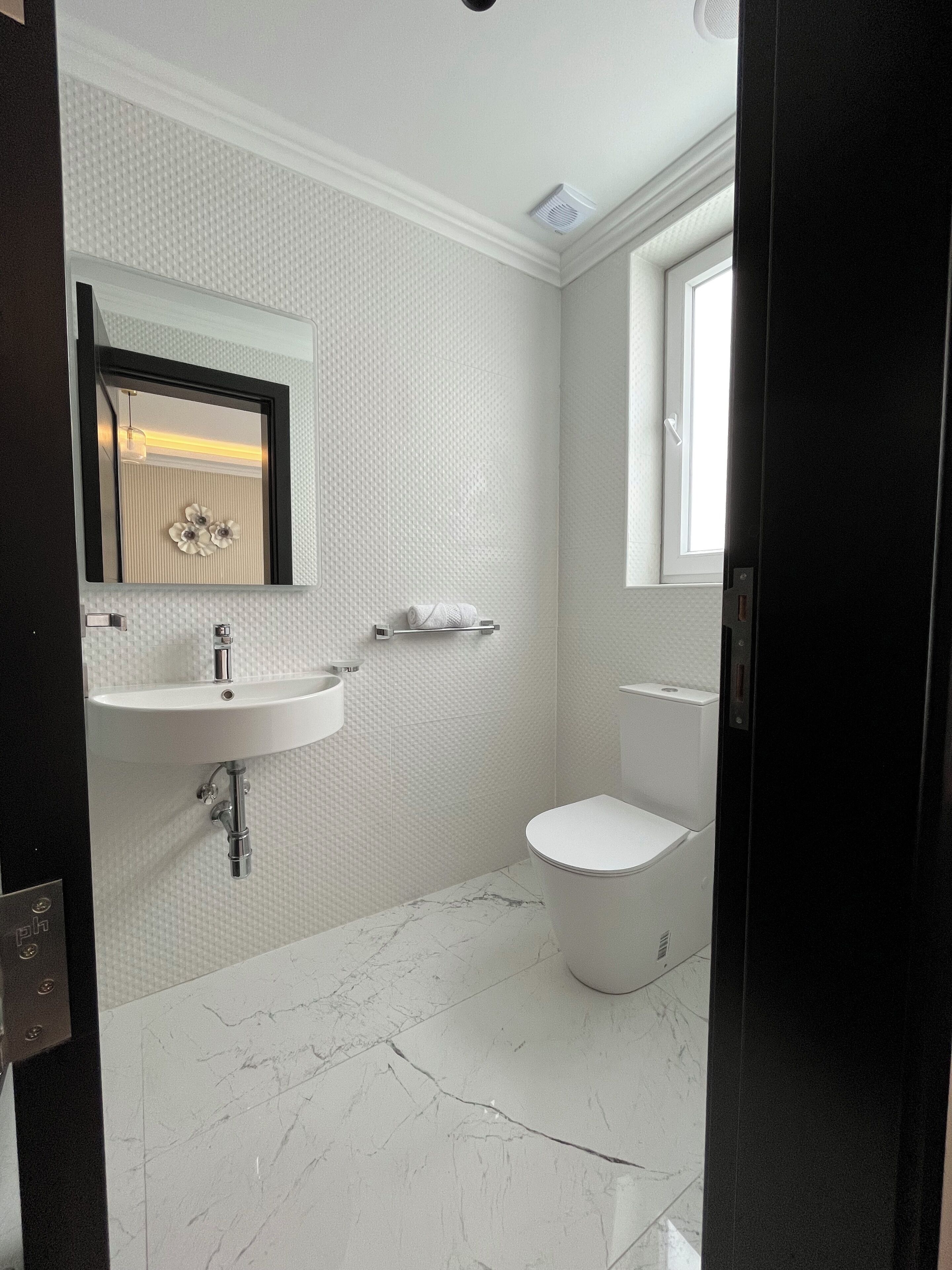 A bathroom with a white sink, mirror, and toilet.