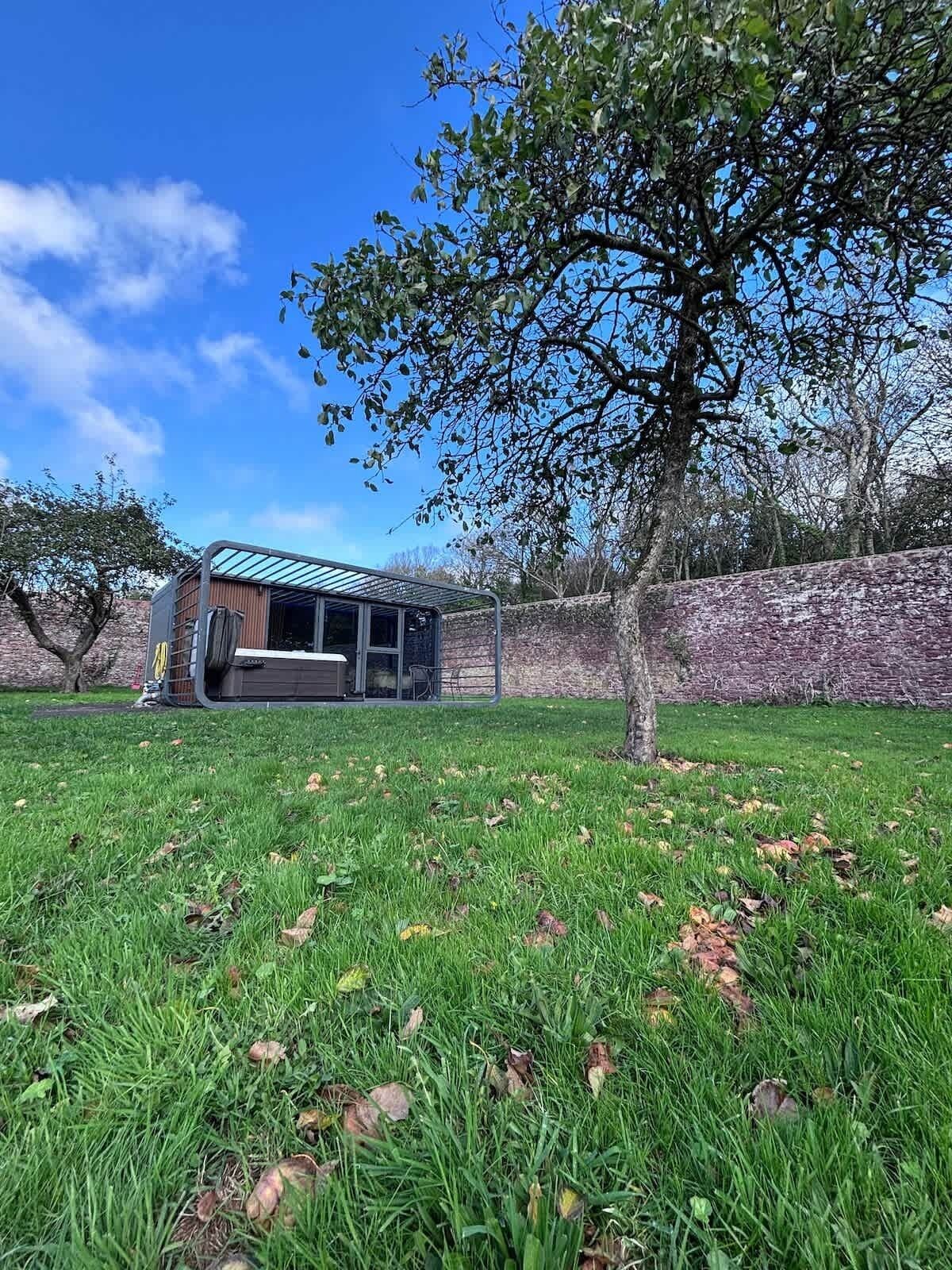 A house with a glass extension, a stone wall, and a grassy yard.