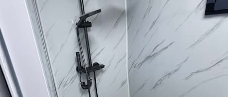 A shower area with a handheld showerhead and a fixed showerhead mounted on the wall.