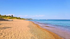 A beach with a boat on the sand, calm sea, and clear sky. - Eneos Boutique Residence - Koroni Garden Gem (Pylos-Nestoras)