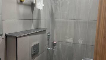 Un baño con ducha, inodoro, lavamanos y toallero.