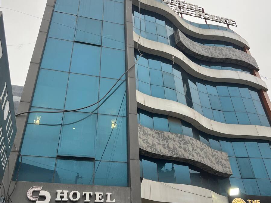 Un hotel de varios pisos con diseño moderno, que cuenta con grandes ventanales y un letrero llamativo que dice "Hotel AC Room".