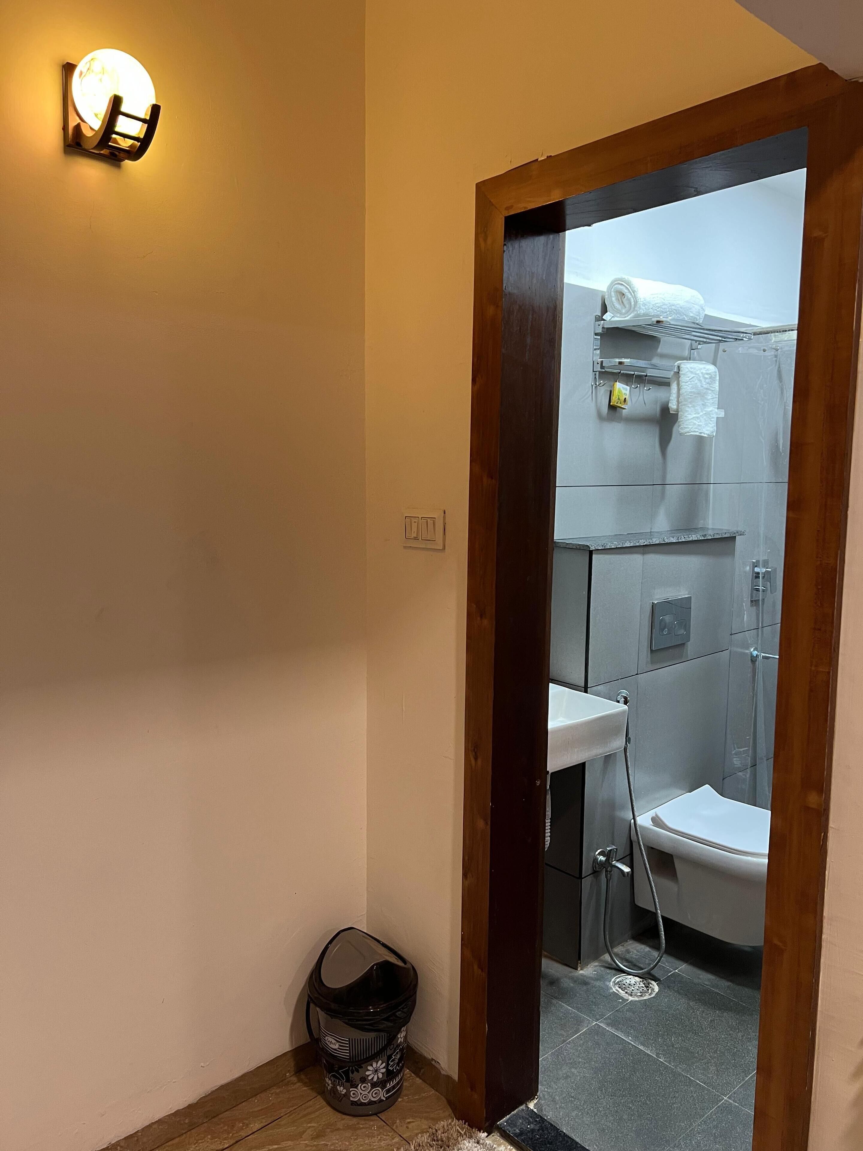 A bathroom with a toilet, sink, and shower. There is a basket and a towel rack visible.