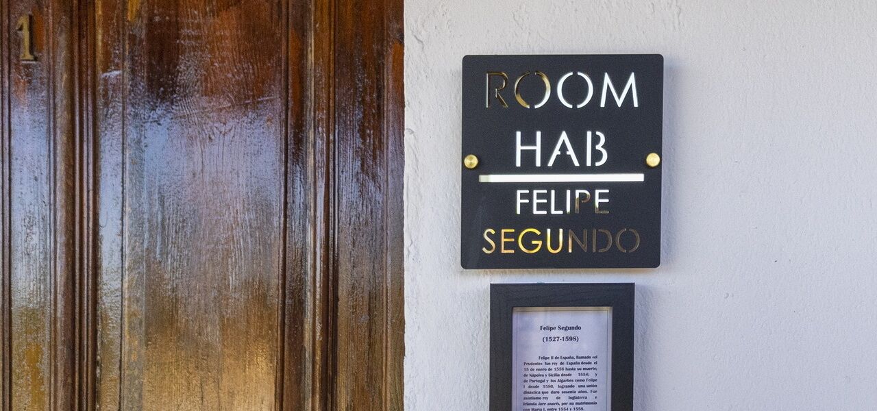 A sign for 'ROOM HAB FELIPE SEGUNDO' with a plaque below it.