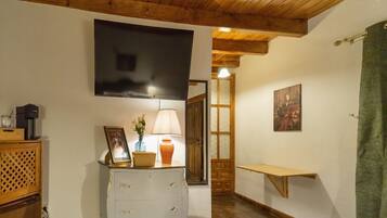 Une pièce chaleureuse avec un plafond en bois, une commode blanche à tiroirs, une petite table avec une lampe et un tableau accroché au mur.