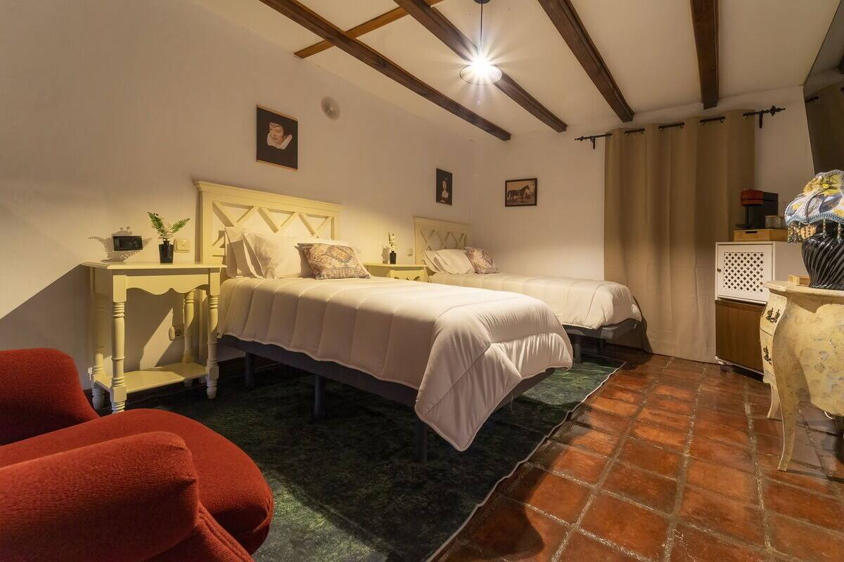 Une chambre avec deux lits, une petite table, une chaise et un vase décoratif.