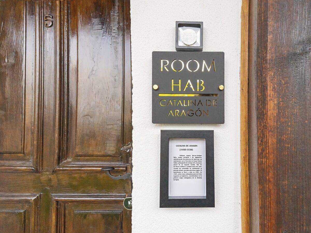 A wooden door with a plaque that reads "ROOM HAB" and "CATALINA DE ARAGON (1485-1536)".