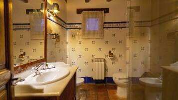 A bathroom with a sink, toilet, and mirror. The walls have a patterned tile design.
