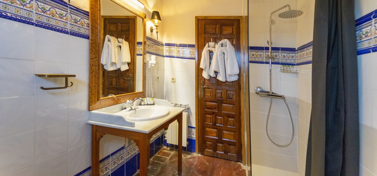 A bathroom with a sink, mirror, and shower.