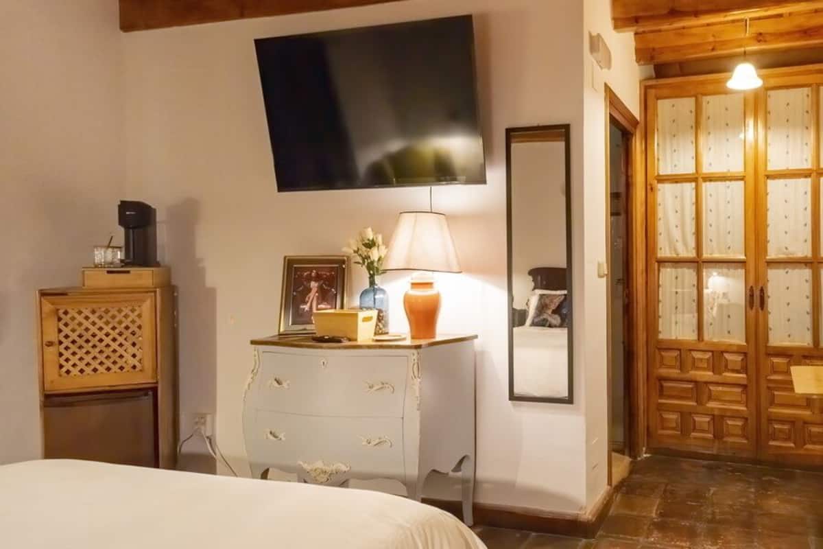 Une chambre à coucher comprenant un lit, une commode, un miroir et une armoire en bois dotée d’une porte en verre.