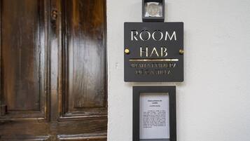 A sign for 'ROOM HAB JUANA PRIMERA DE CASTILLA' with a plaque below it.