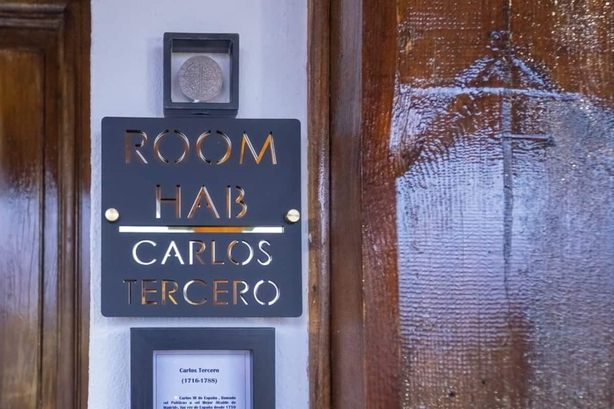 Une pancarte indiquant la salle numéro 7, nommée en l’honneur de Carlos Tercero, avec une plaque commémorative en dessous.
