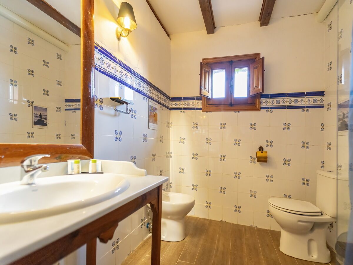 A bathroom with two sinks, a toilet, and a window.