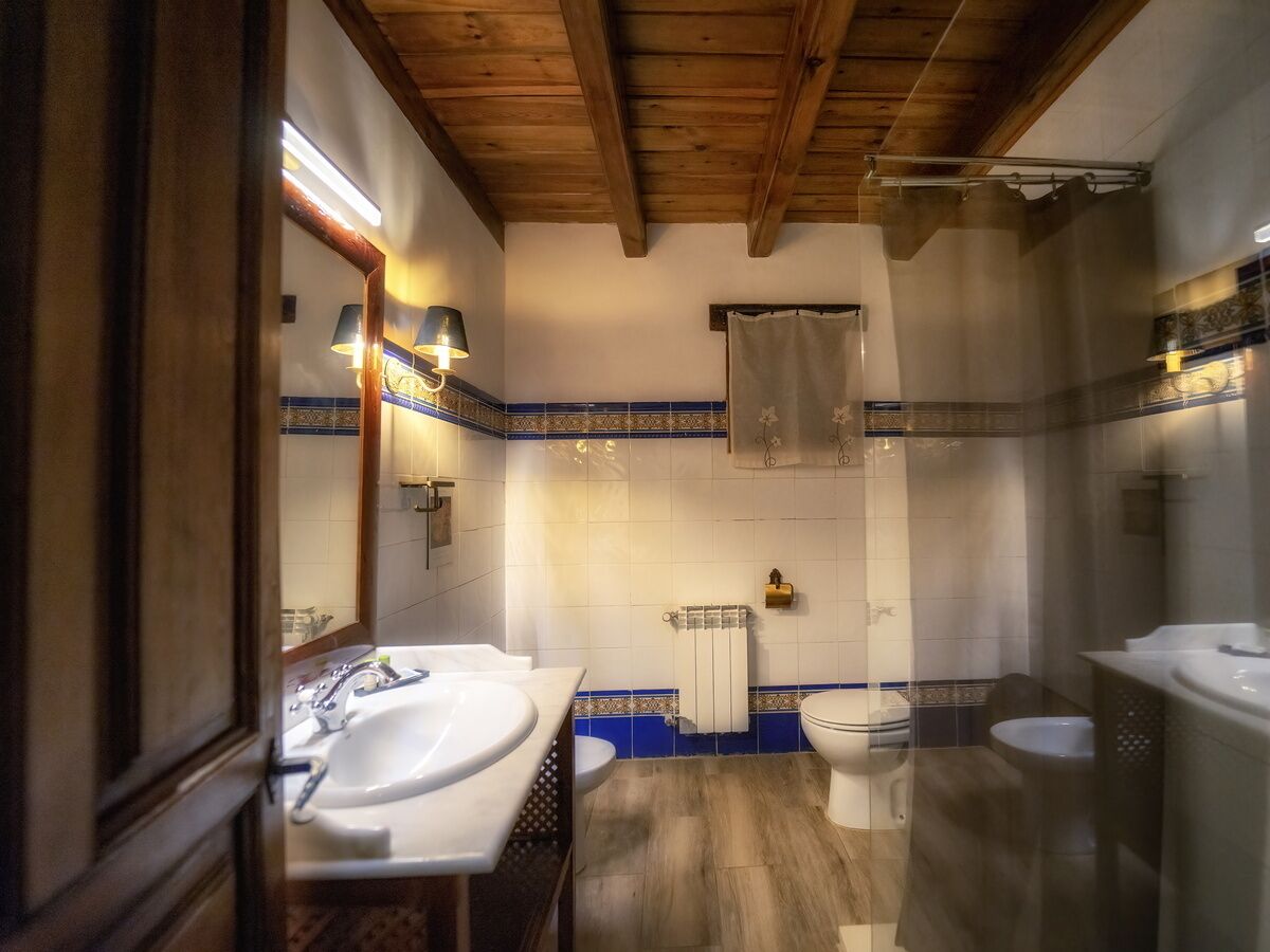 Ein Badezimmer mit Holzboden, einem Doppelwaschbecken, einer Toilette und einer Badewanne.