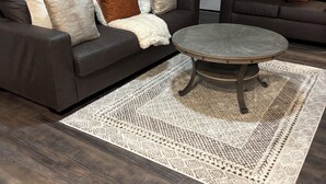Un salon avec deux canapés de couleur marron foncé, une table basse ronde et un tapis à motifs.