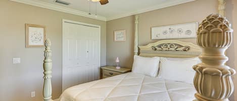 A bedroom with a bed, a nightstand, a dresser, a ceiling fan, and a door.