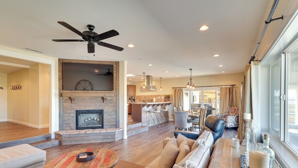 A spacious living room with a fireplace, a ceiling fan, and a large window. - Enjoy Million-dollar Views! Lake Havasu City Home (Lake Havasu City)