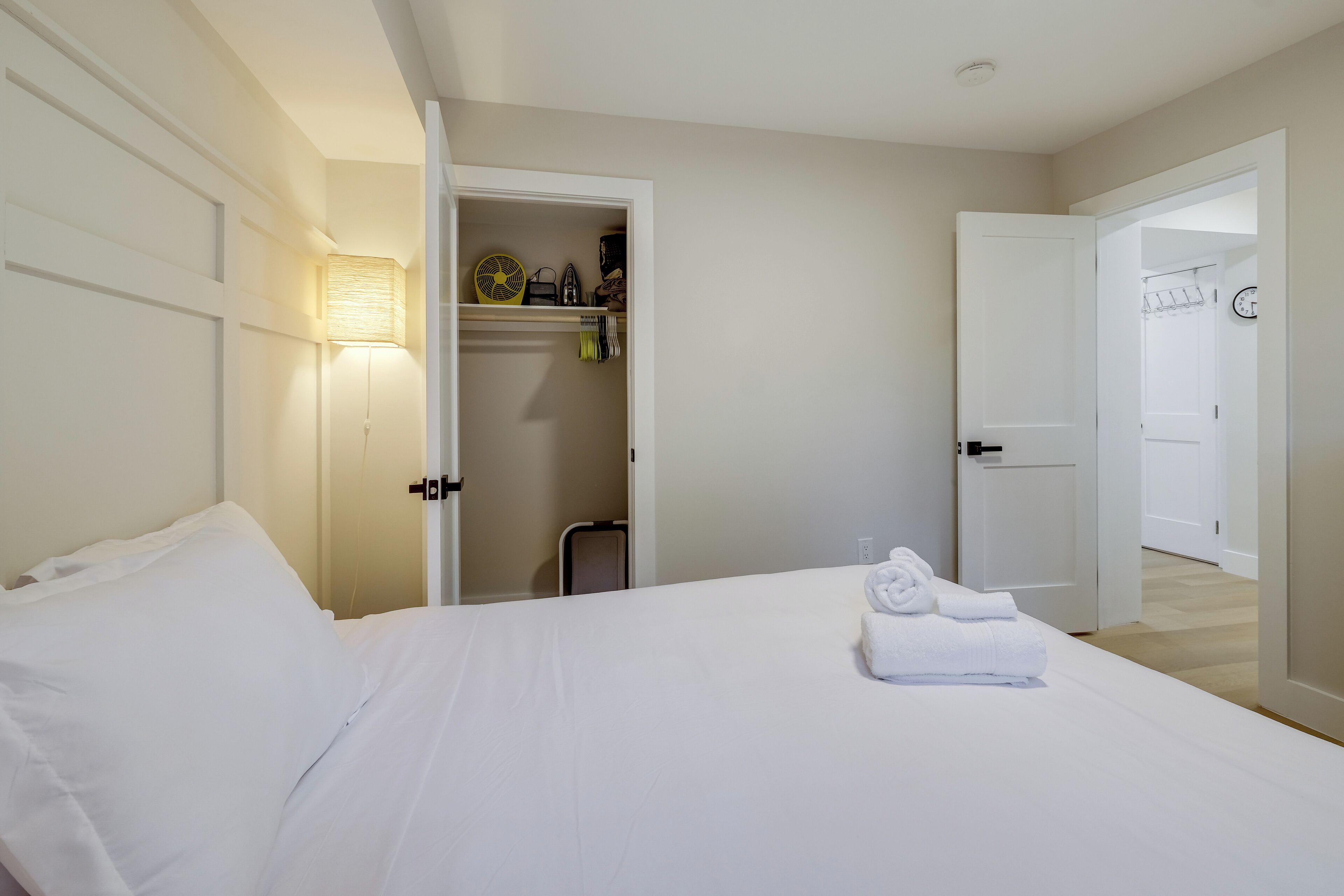 A hotel room with a bed, a closet, and a door leading to another room.