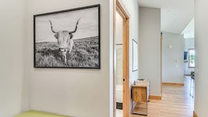 A hallway with a framed black and white photograph of a longhorn on the wall, a wooden bench, and a view into a room with a window. - 5 Mi to Winter Park Skiing & Dtwn: Mtn-view Condo (Fraser)