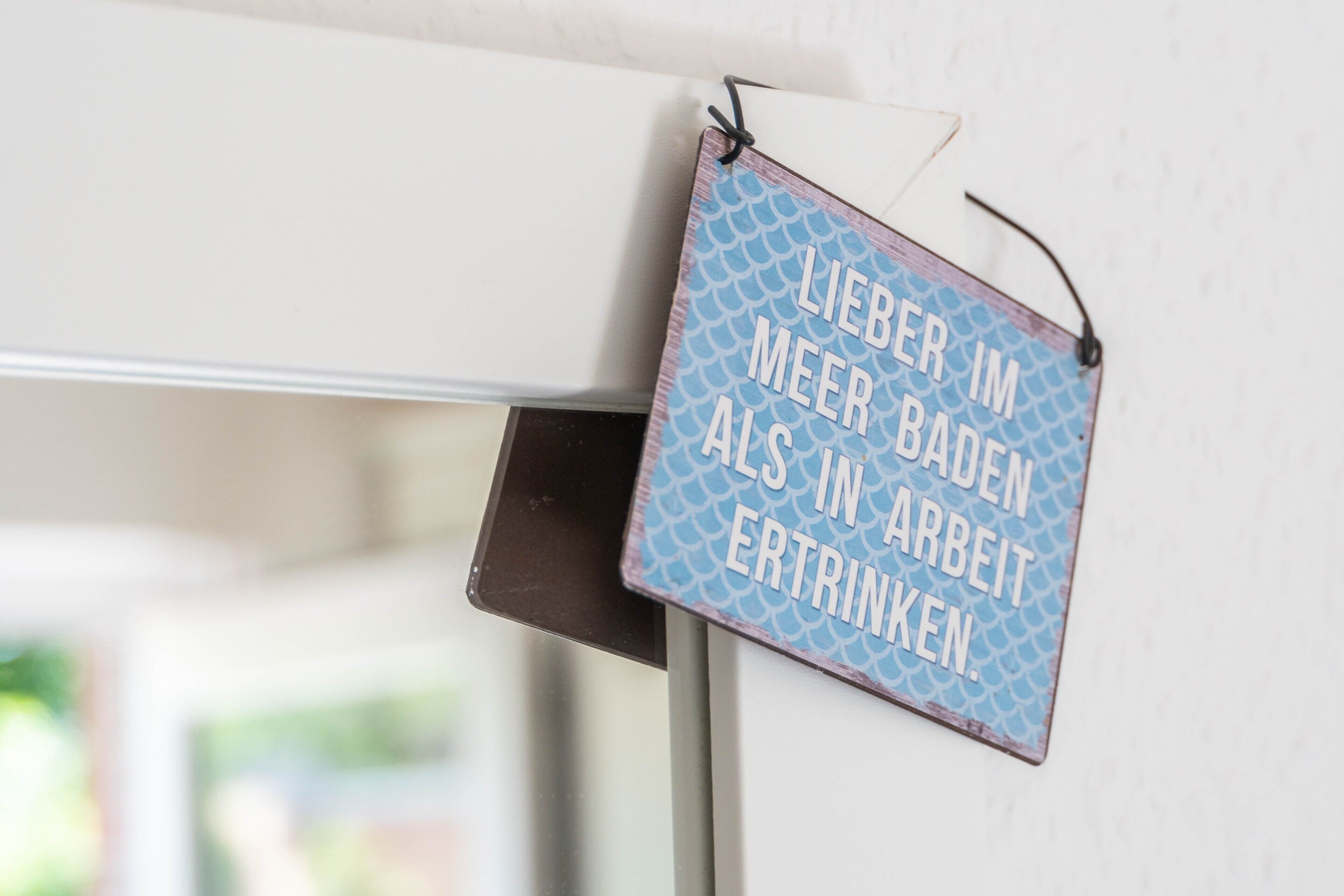 Ein an einer Wand befestigtes Schild mit deutschem Text.