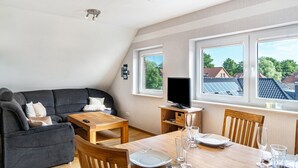 Een moderne woonkamer met een bank, eettafel en televisie.