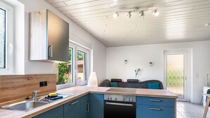 Moderni keittiö, jossa on puinen työtaso, integroidut kaapit, liesi ja pesuallas.