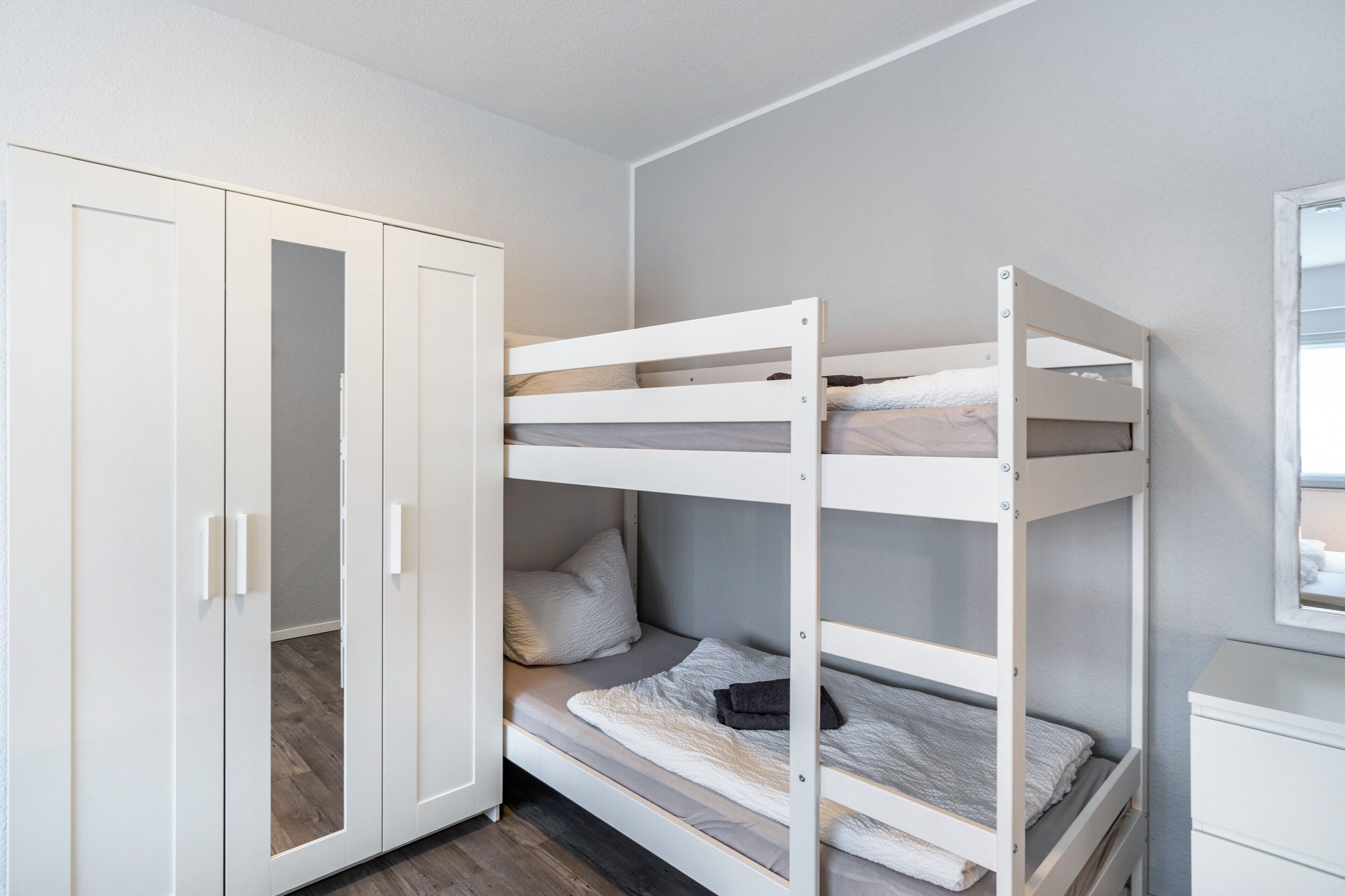 A bunk bed room with a wardrobe and a small desk.